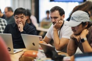 Team of professionals closely reviewing options on laptops during vendor research, illustrating how G2 and Capterra reviews factor into B2B buying decisions