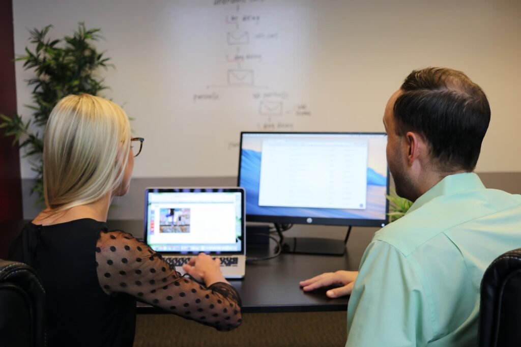 Two colleagues reviewing performance data on screen, illustrating what an AI visibility agency does month by month